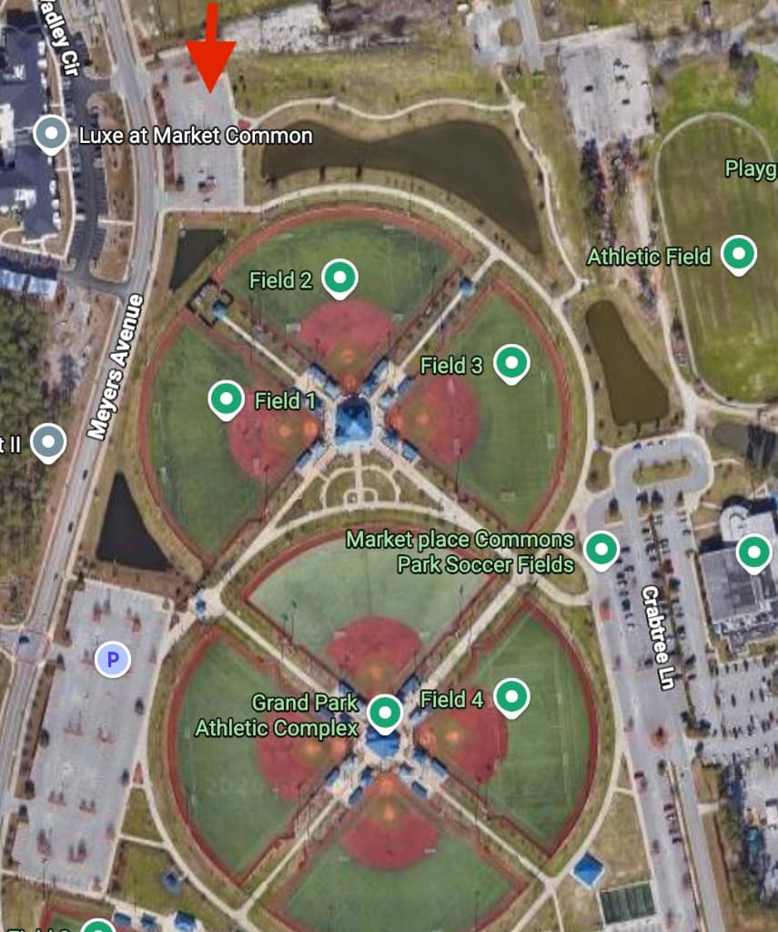 Satellite map of Grand Park at Market Common showing the recommended venue meetup area marked with a red arrow at the northern parking lot off Meyers Avenue near Luxe at Market Common